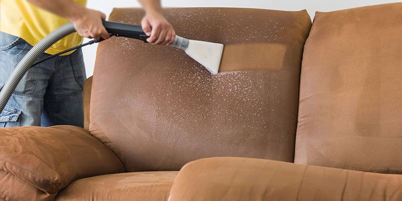 A Person Cleaning A Sofa By Using Sofa Cleaner.